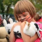Best Rabbit Breeds for Kids: Gentle, Cuddly & Beginner-Friendly Choices little girl with painted tiger face holds rabbit